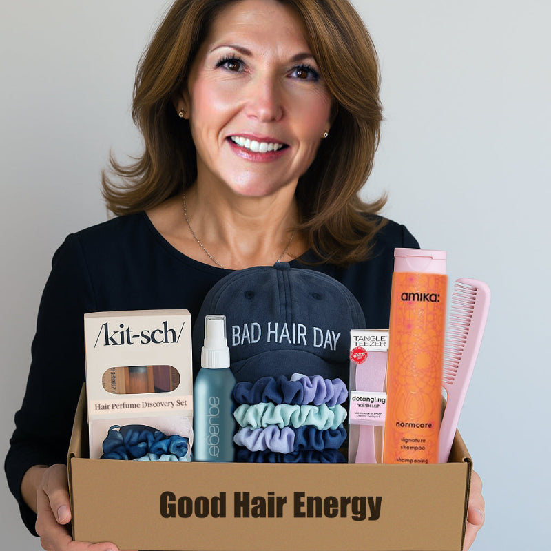Woman holding a box labeled 'Good Hair Energy' with hair care products inside.